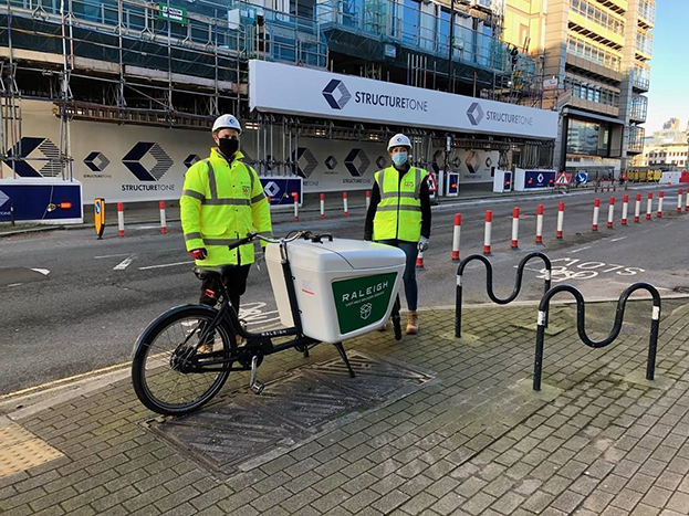 Two construction workers use a bike to reduce their carbon footprint
