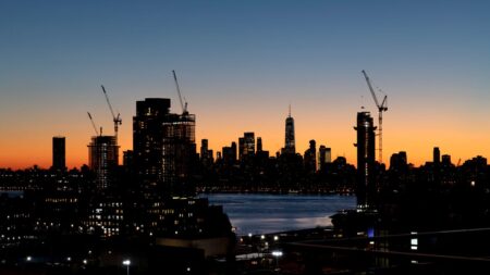 mass timber, Construction cranes line the city skyline at dusk in New York City