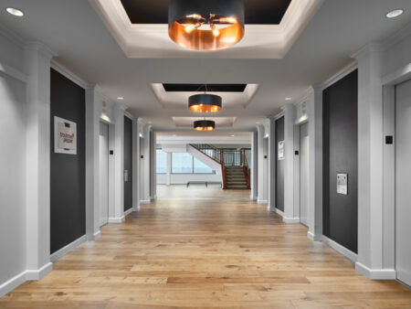 An office hallway with polished wooden floors and white walls.
