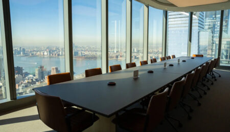 A conference table in a spacious room overlooking the city skyline.