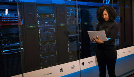 A woman with a laptop standing in front of data center technology