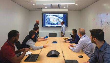 A group of people in a conference room discussing what is on the projector.