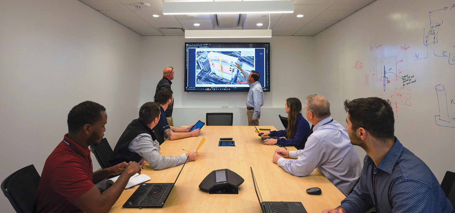 A group of people in a conference room discussing what is on the projector.