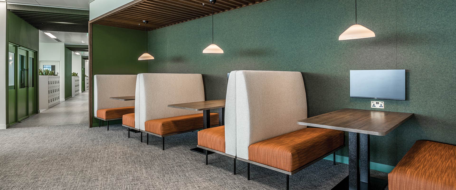 Several booths along side a green while for seating and collaboration.