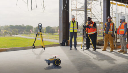 A group of construction workers wearing full PPE on a job site using robotics.