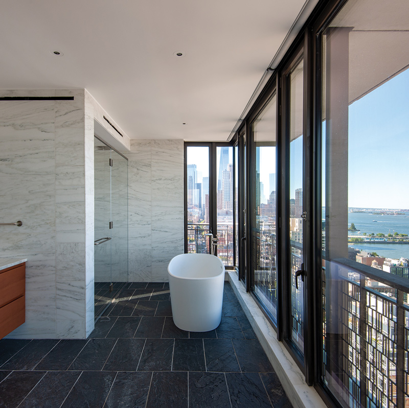 A spacious bathroom featuring a large window that offers a panoramic view of the city skyline.