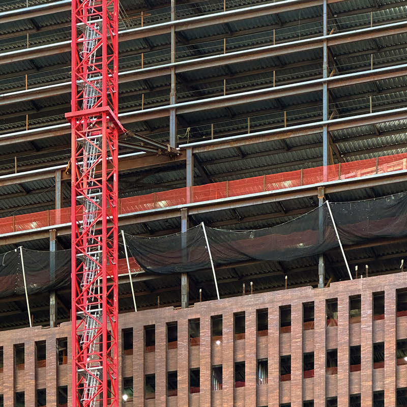 A red crane positioned next to a building under construction.