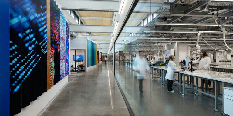 A long hallway in a lab with several people engaged in various work activities.