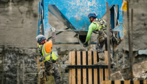 Two construction workers collaborating on a construction site, wearing safety gear and focused on their tasks.