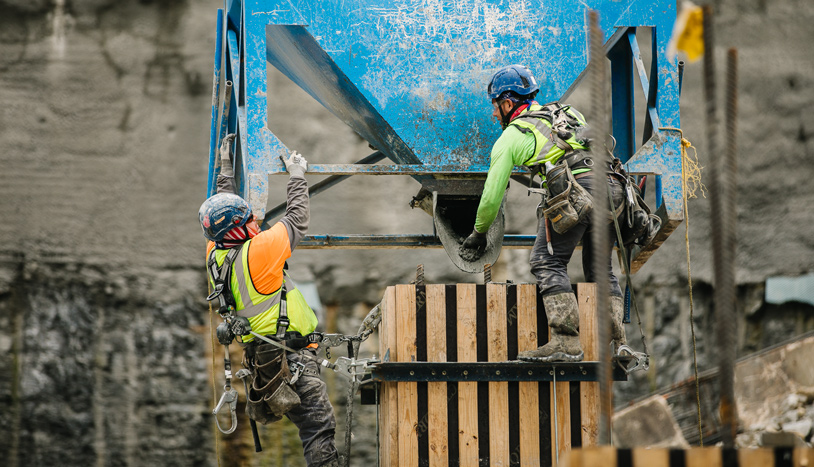 Two construction workers collaborating on a construction site, wearing safety gear and focused on their tasks.