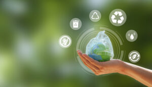 green tree background with a hand holding a miniature trash bag and recycle emojis floating in a circle around it