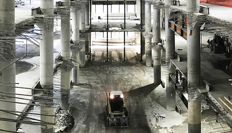 441 ninth interior image of a construction site with a machine on the ground floor with rebar peeking through many floors