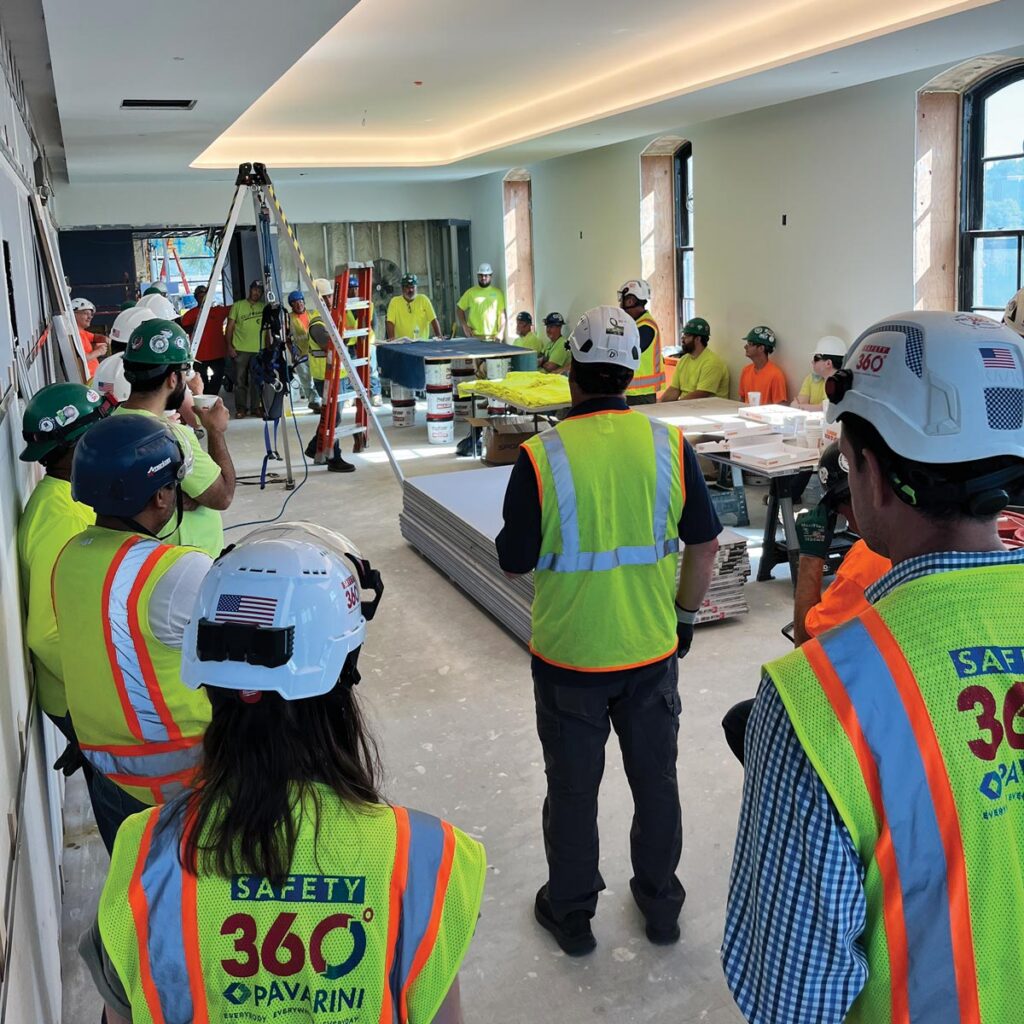 A group of construction workers listening to a safety demonstration on the project site.