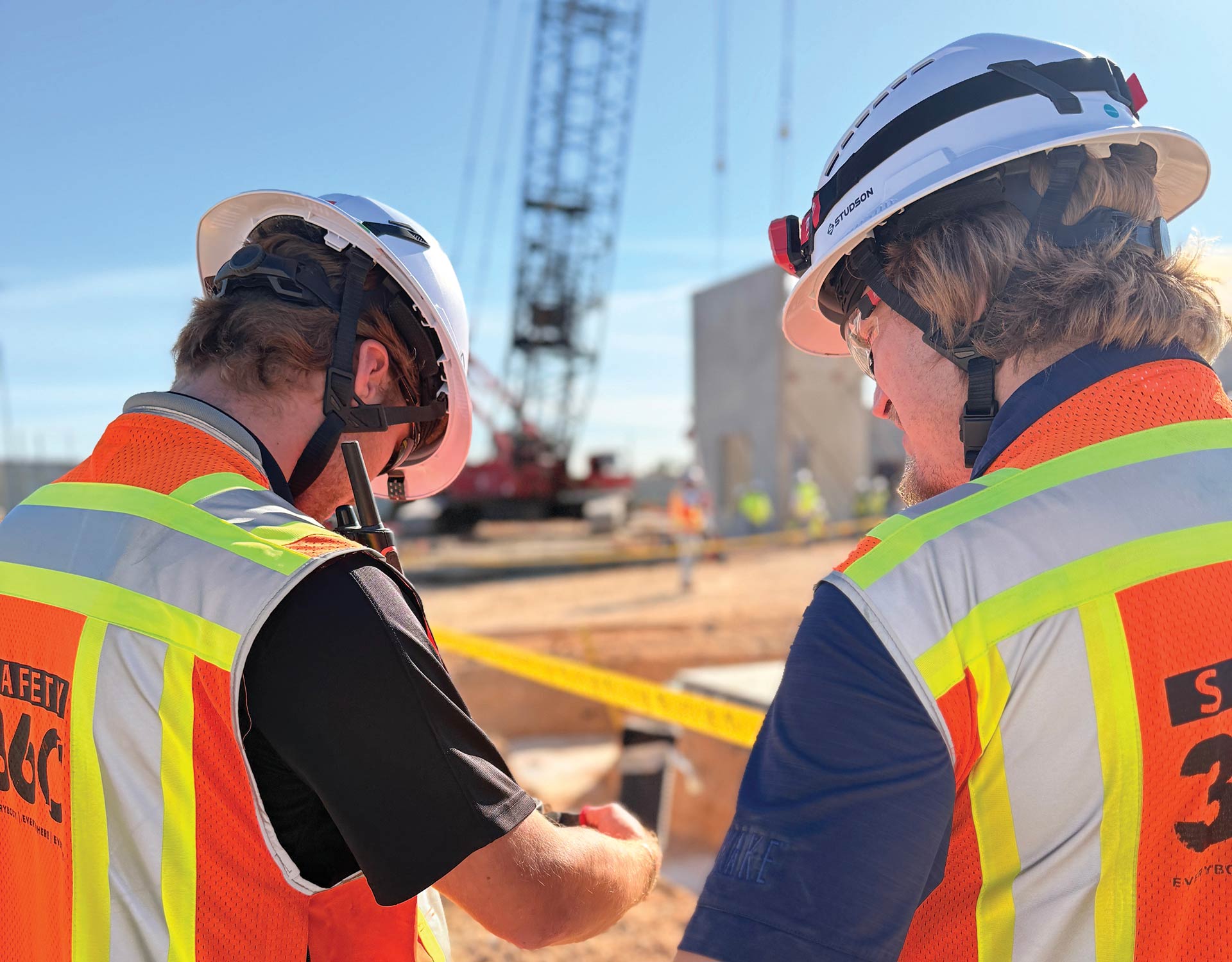 Two construction workers wearing full PPE on a jobsite.