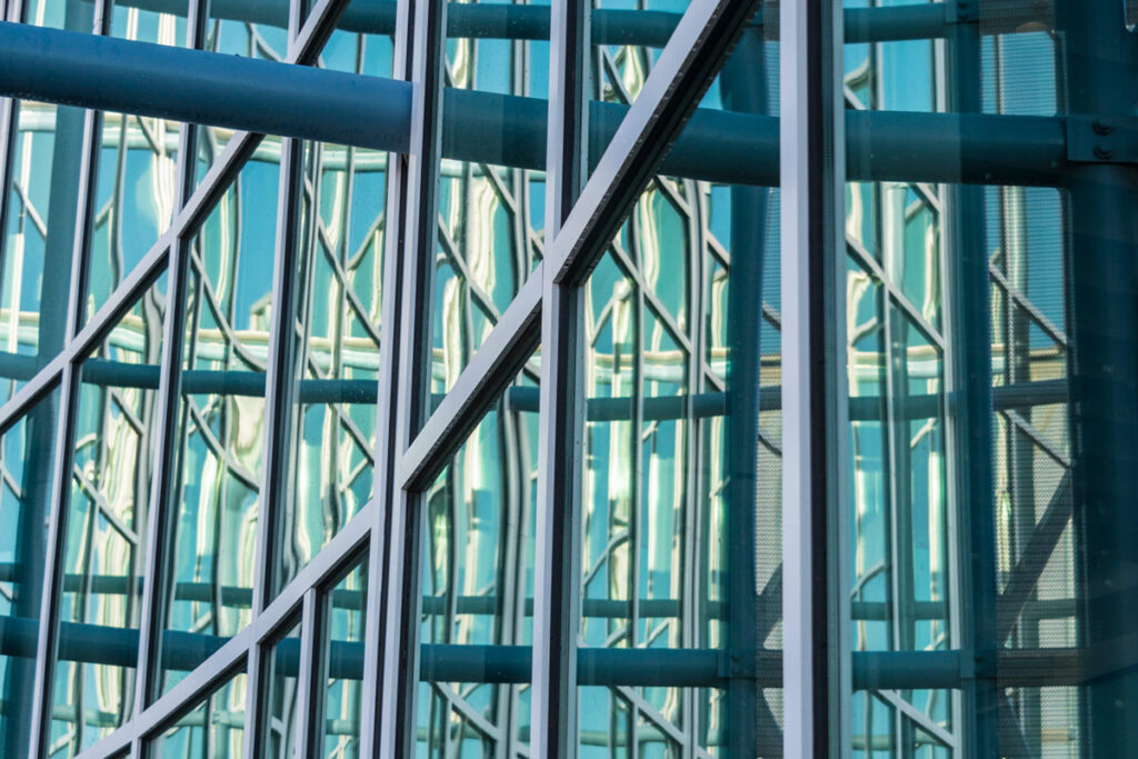 Close-up view of a modern glass building façade featuring curved architectural lines and a grid of metal-framed windows.