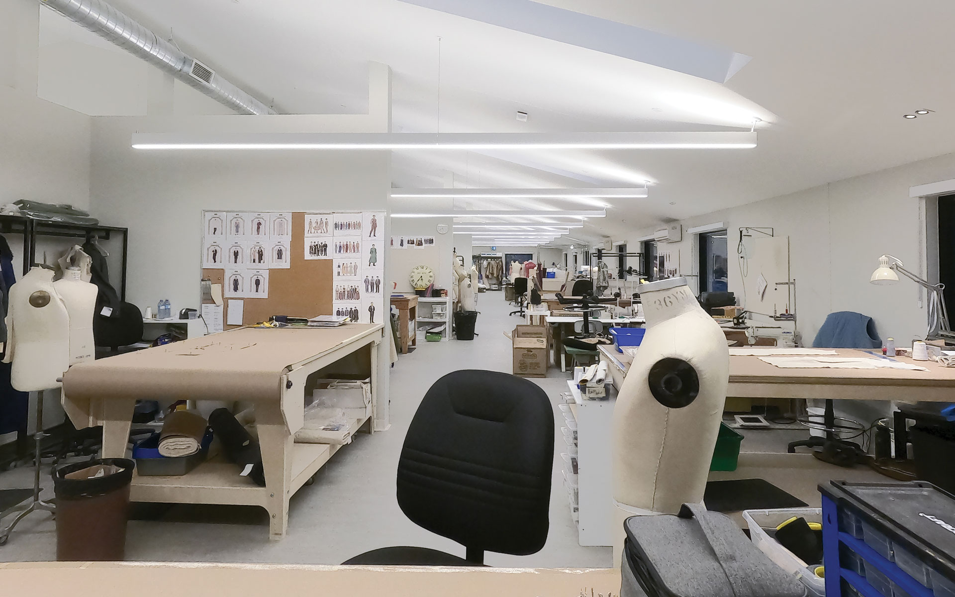 Clothing design room, with mannequin's, interesting light structures, and grand tables.