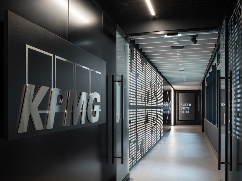 KPMG office corridor with a metallic logo and illuminated geometric wall panels.