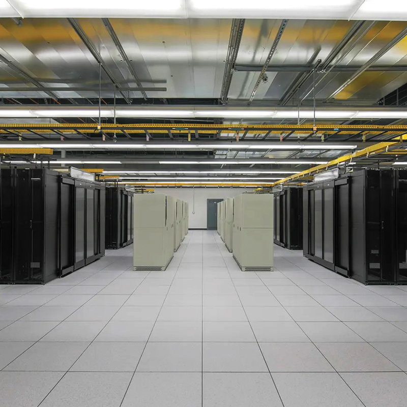 Data center interior with rows of black and light-colored equipment cabinets, a raised tile floor, and overhead cable trays.