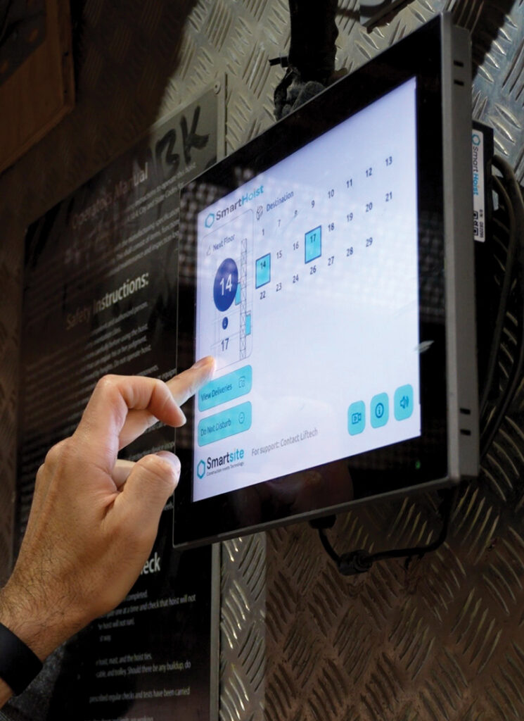 Hand using a SmartHoist touchscreen displaying floor destinations and elevator controls.